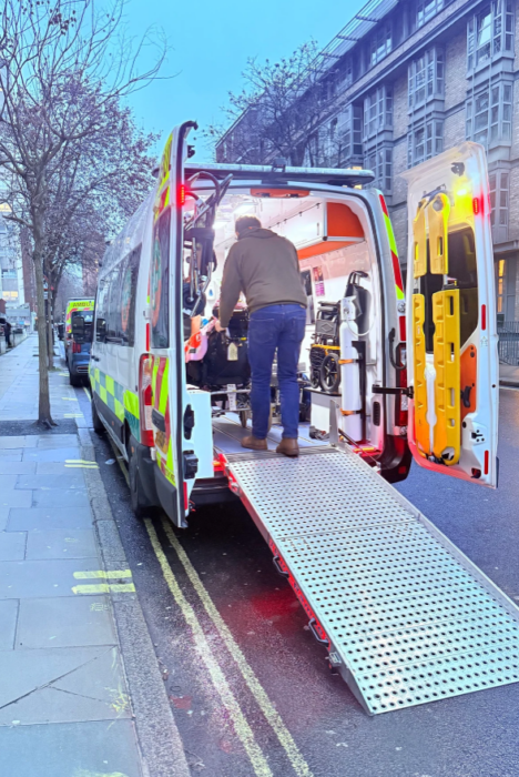 Qualified paramedic crew loading a patient into a private ambulance for urgent medical transport in London