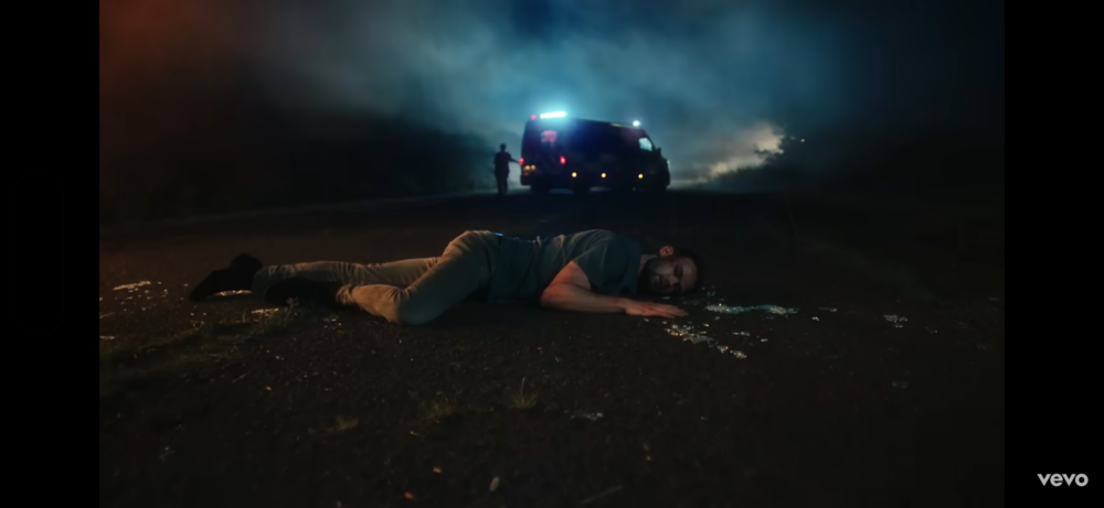 Film production emergency scene with ambulance vehicle and actor lying on road during night filming 